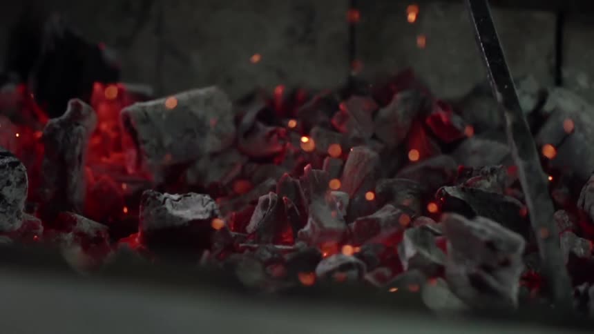Hot coals are being mixed around with a poker