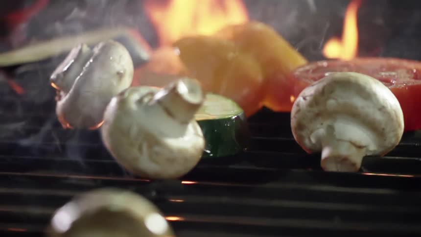 Mushrooms tumble on a metal grill while cooking