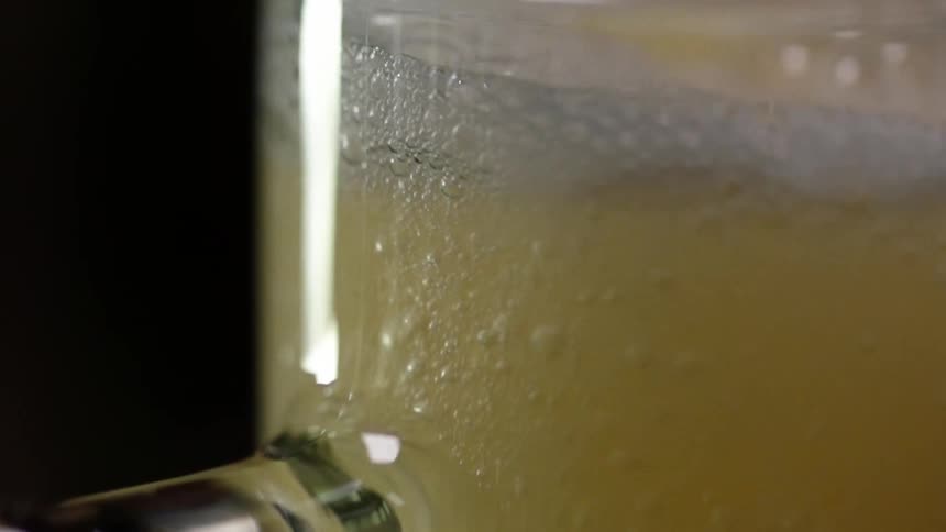 A light colored beer fills a glass mug