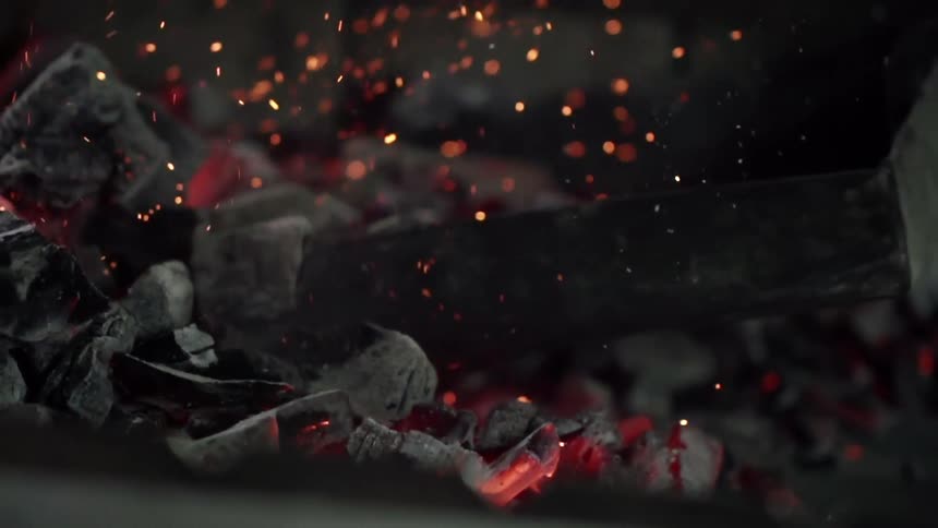 Embers fly about as coal is moved around with a coal shovel