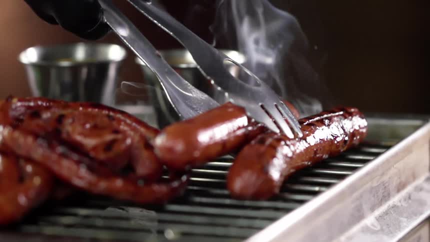 A person puts meat on a grill