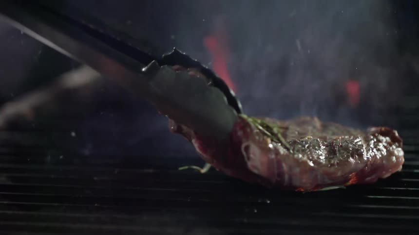 A steak is placed on the hot grill