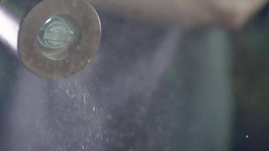Salt from a shaker sprinkles out as steam rises