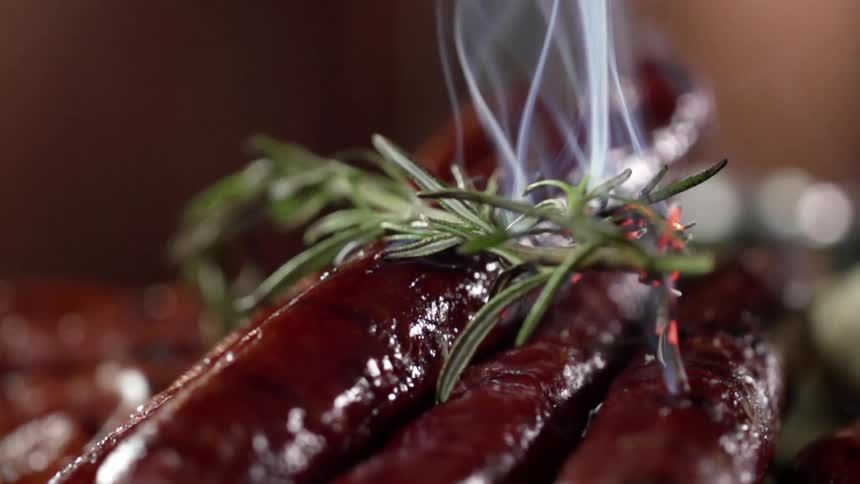 Sausages cook with herbs placed on top of them
