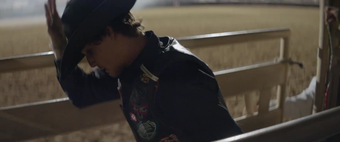A rodeo rider exits the gate on a bull