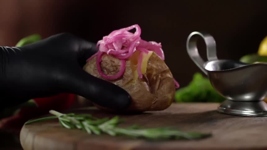 A baked potato is placed on the cutting board