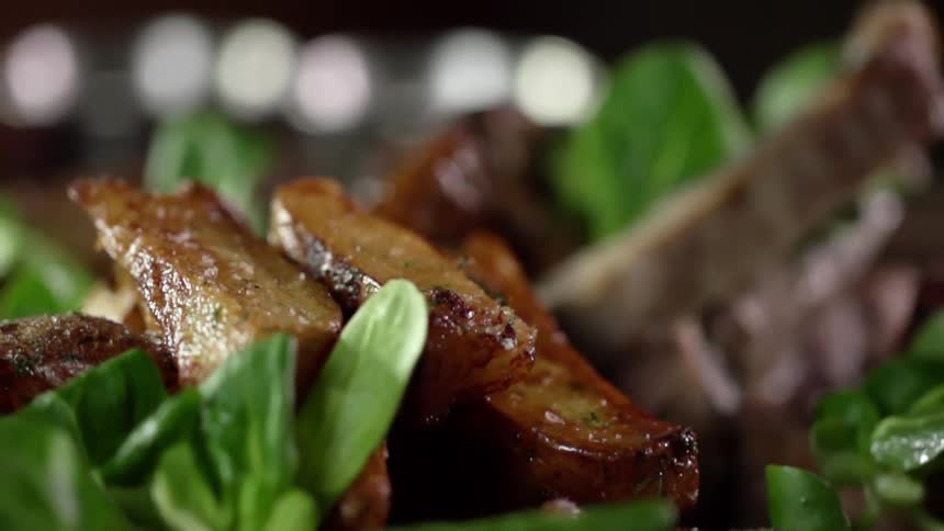 Strips of cooked pork and fried potatoes over leafy greens