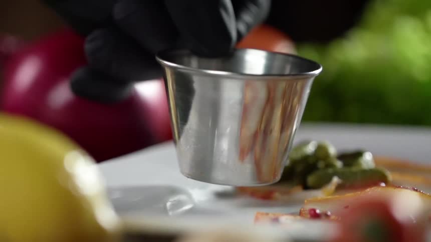 A person puts a container on a plate as they plate a meal