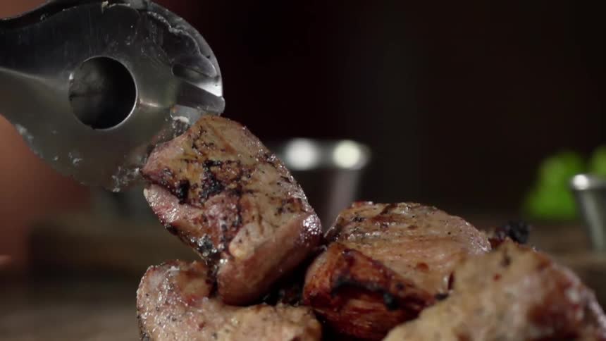 A chunk of meat is slid off of a metal skewer