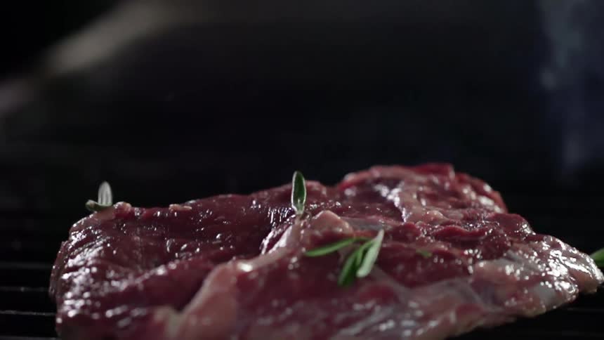Herbs are dropped on meat as it cooks