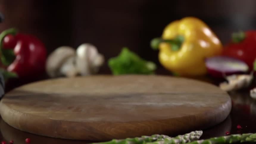 A hand wearing a black glove puts a wooden platter down on a table