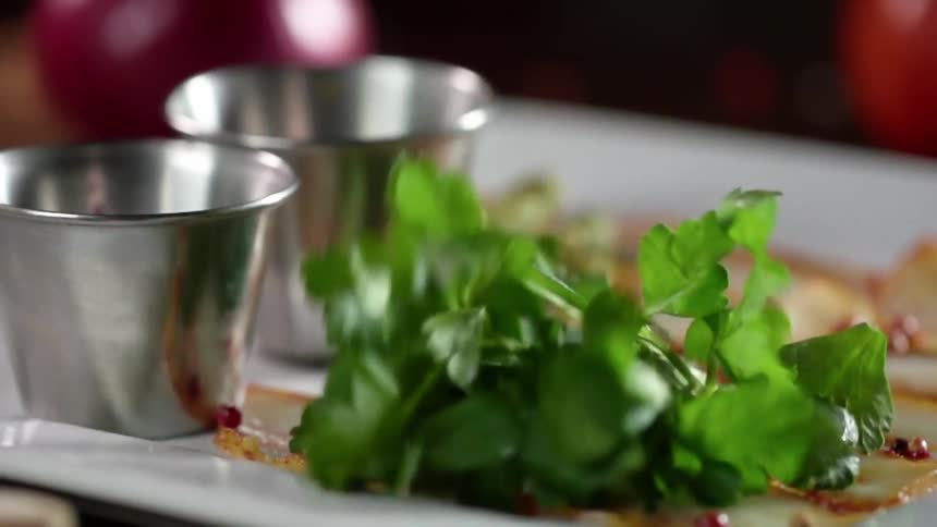 Herbs being put on a plate with food