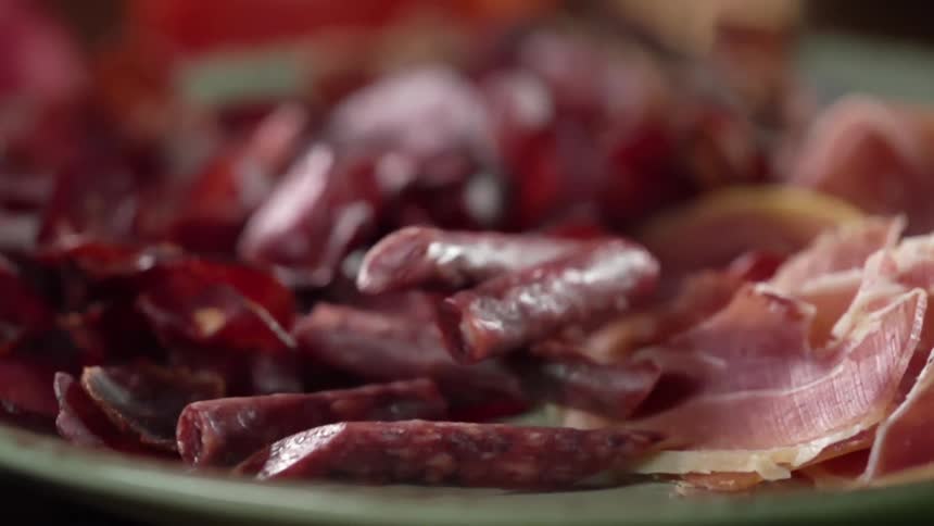 Sliced sausages falling on a charcuterie plate
