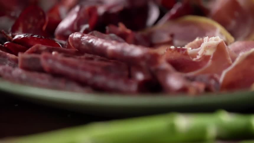 Asparagus spears next to a platter of cured meats