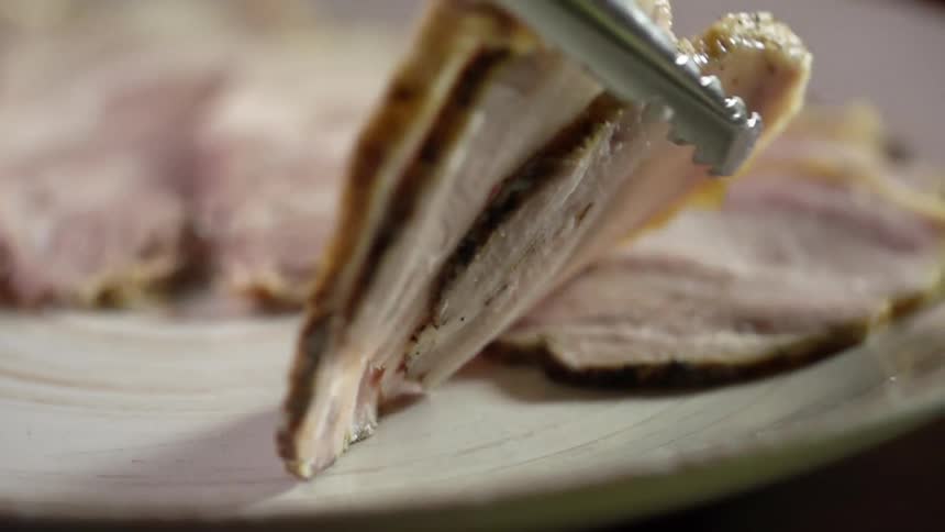Thin slices of roasted pork are gently laid on a glass plate along with several other slices