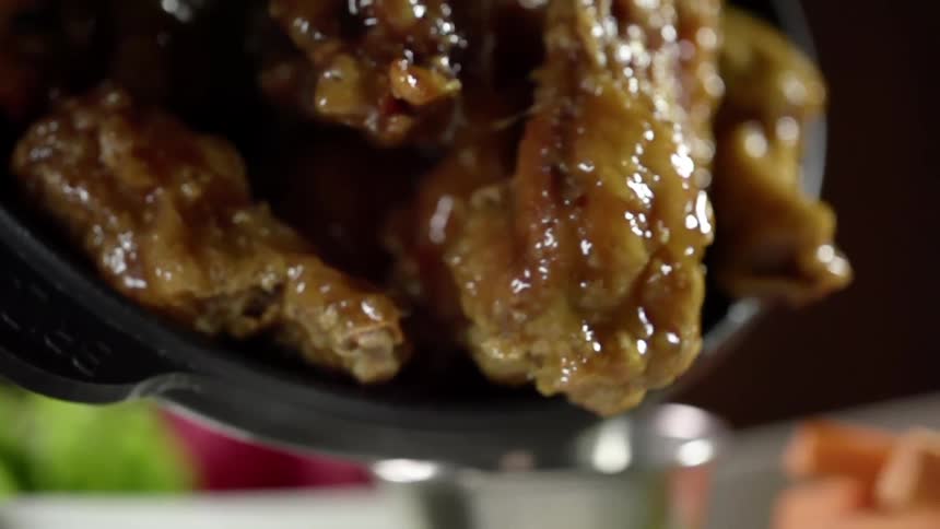 Several pieces of battered and fried chicken covered in gravy are poured from a pot