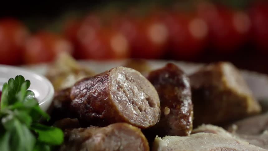 Sliced cooked sausages in a plate near a row of red tomatoes