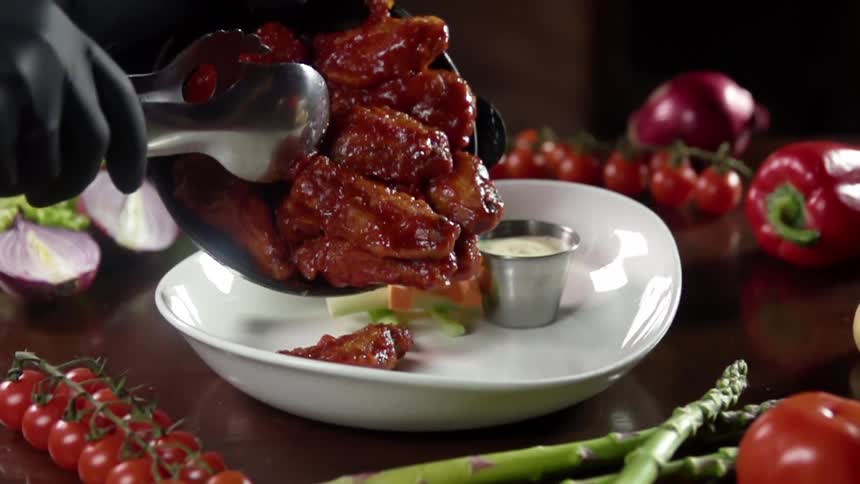 Barbeque glazed chicken wings served from a cast iron pan into a white ceramic bowl