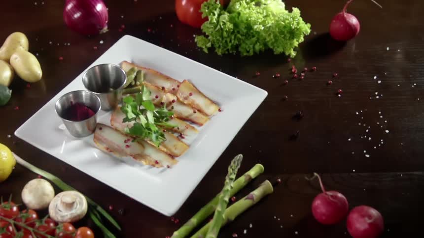 A sprig of parsley is dropped as garnish on plated food surrounded by fresh vegetables