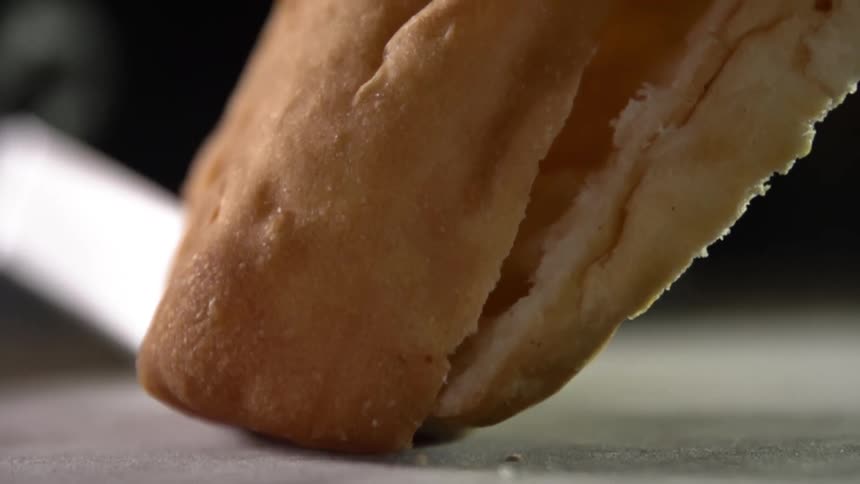 A person cuts some bread in half