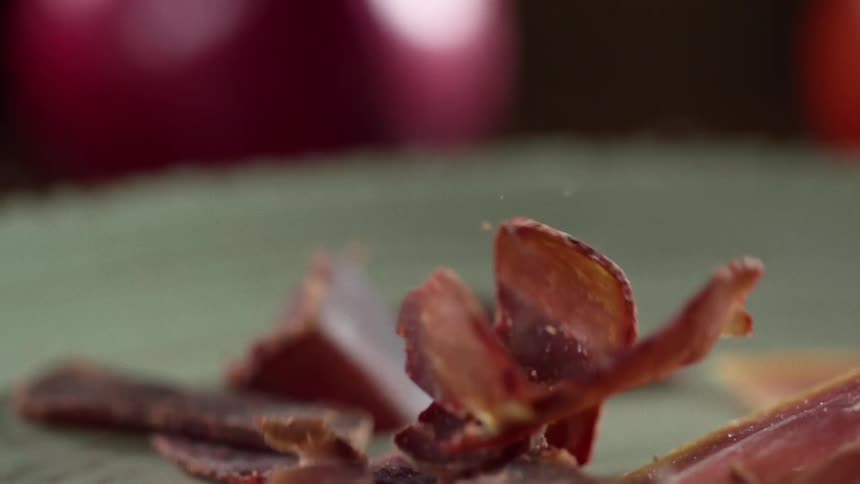 Stiff slices of meat fall onto a green surface