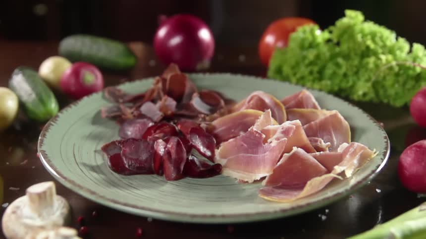Food falling on to a plate with meat on it