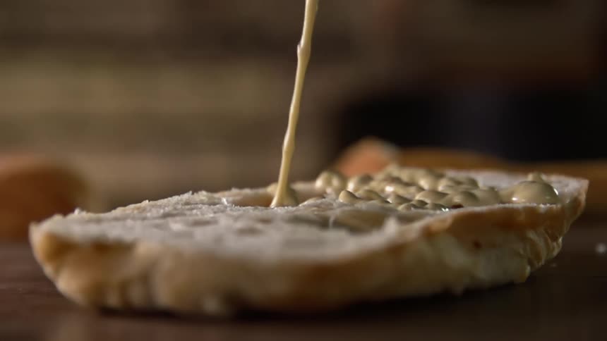 A condiment being put on a bun