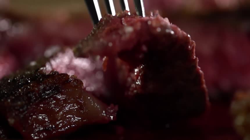 A fork picks up a piece of steak