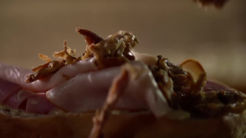 Garnish drops from above onto a meat sandwich