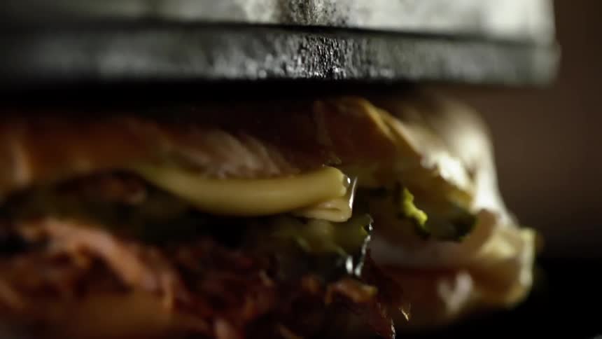 Pork belly sandwich with cheese and vegetables pressed down in a grill