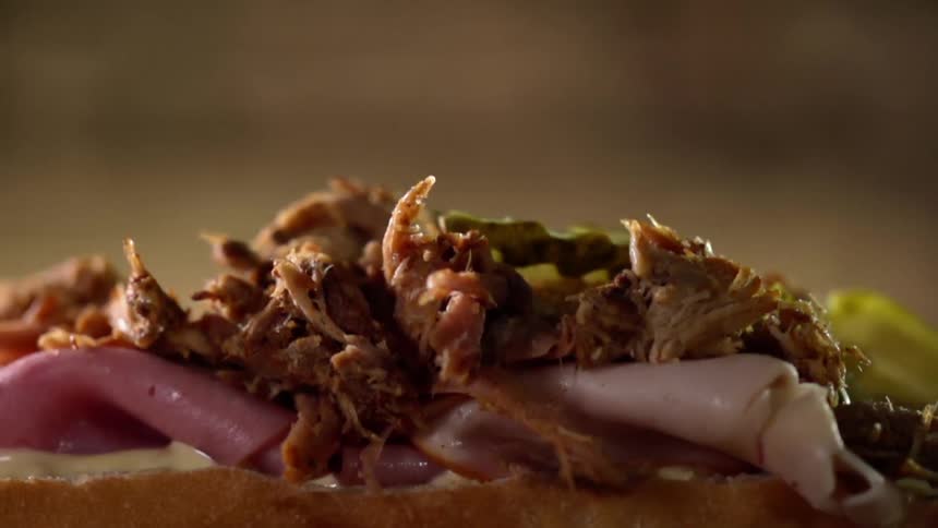 A sandwich is being made with meat and condiments