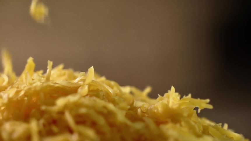 Shaved cheese drops into a pile