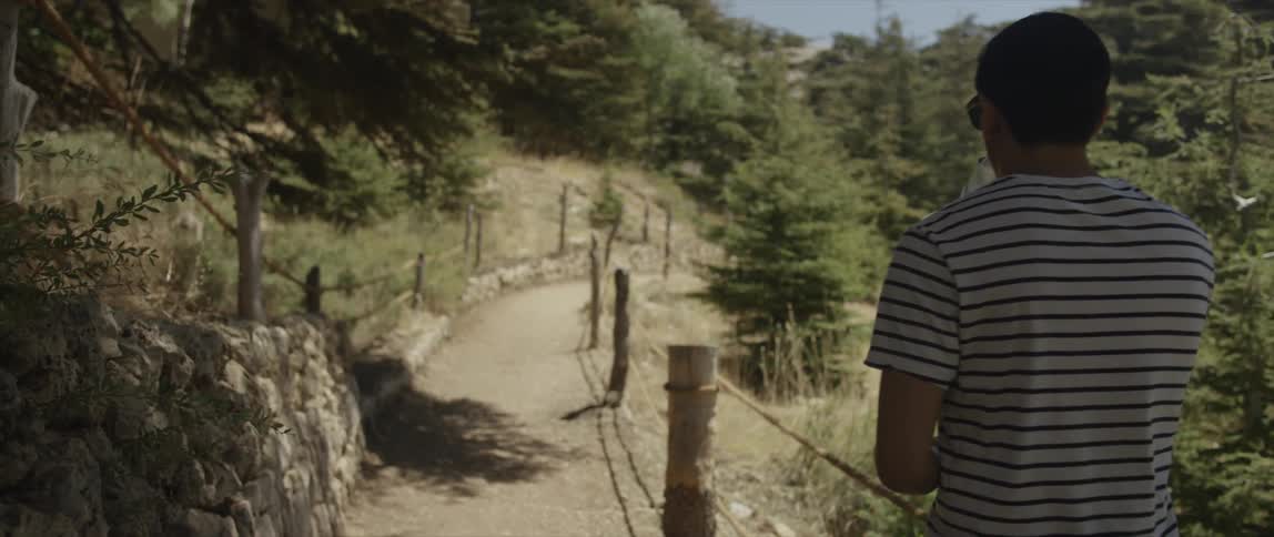 A man is hiking down a trail on a sunny day