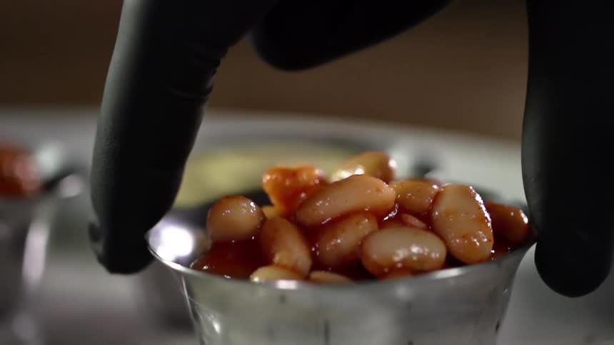 A person sets down a container of beans on a plate