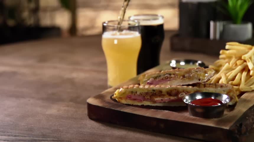 A drink is being poured next to a plate of food on a table at a restaurant