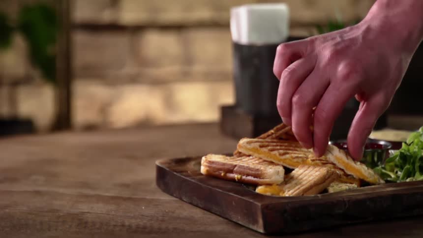 A white male lifts a piece of cheesy bread off of a platter