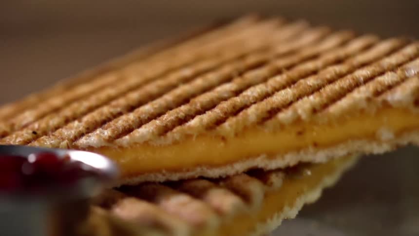 Close up of a toasted sandwich being put on another sandwich