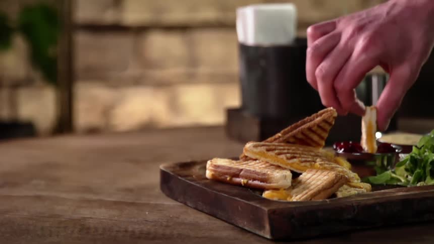 A white male dips a cheesy bread piece into red dipping sauce