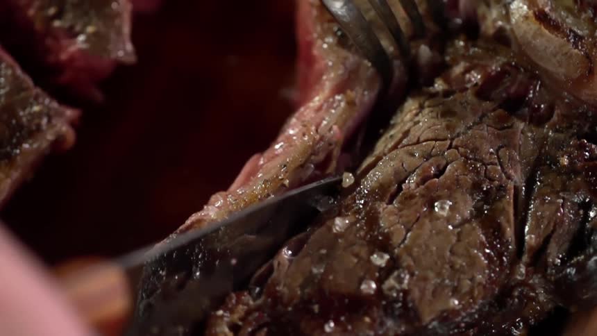 A person cutting in to a piece of meat