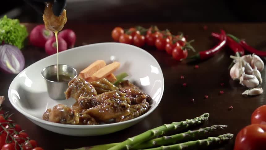 A gloved hand dips a fried food into a ramekin of sauce