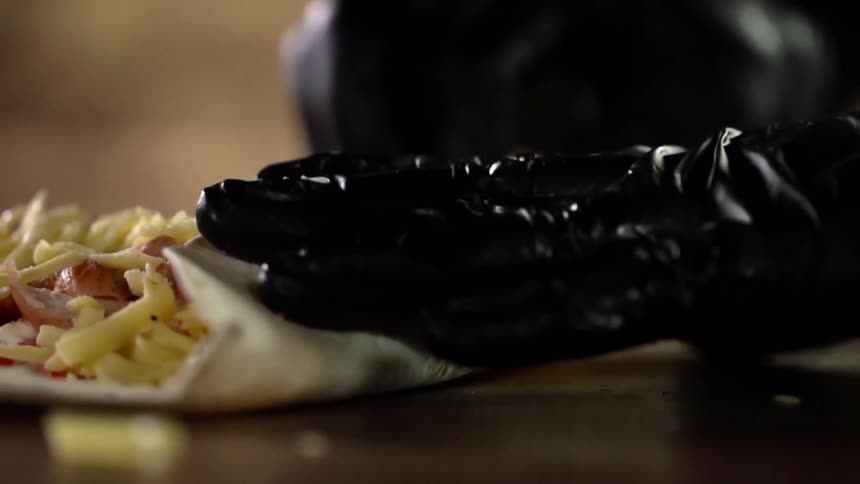 A person folds up a burrito into a tortilla