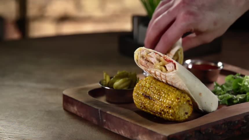 A person at a restaurant picks up a sandwich and dips it in sauce