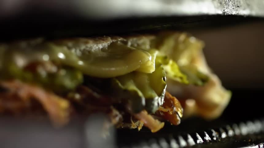 A sandwich cooks inside of a metal press