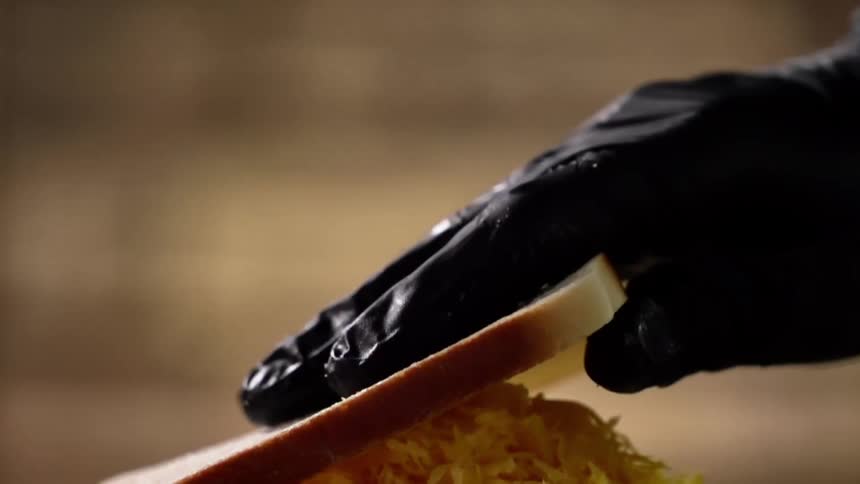 A person puts a piece of bread on top of a sandwich