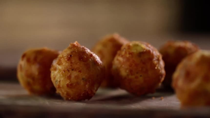 A person puts fried food down on a wooden platter