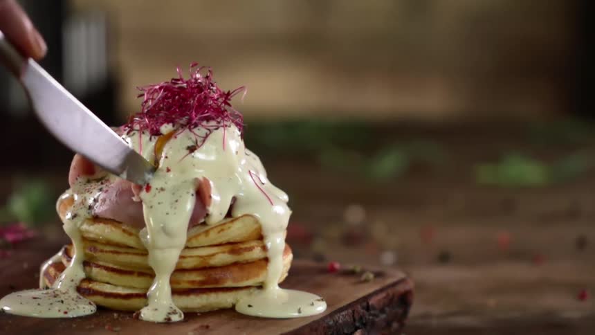 A person cutting a stack of pancakes