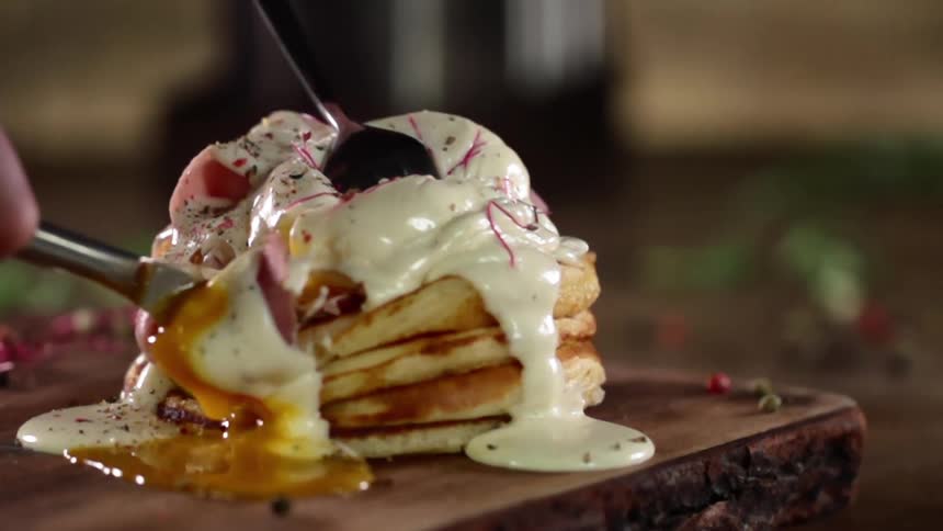 A person is cutting the eggs and pancakes