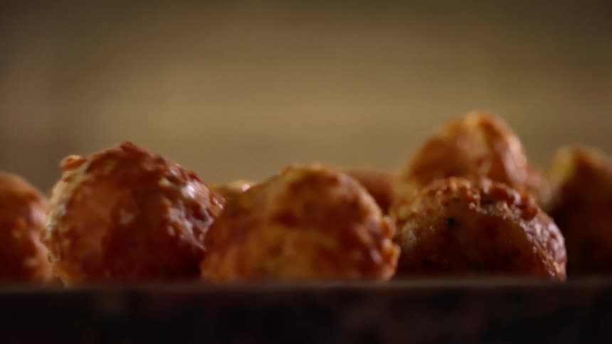 A fried appetizer being put in to a bowl