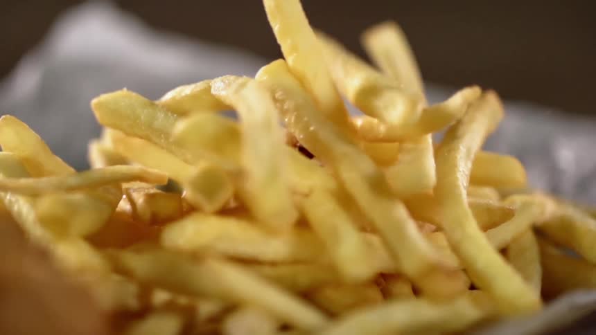 French fries are being dropped on tin foil