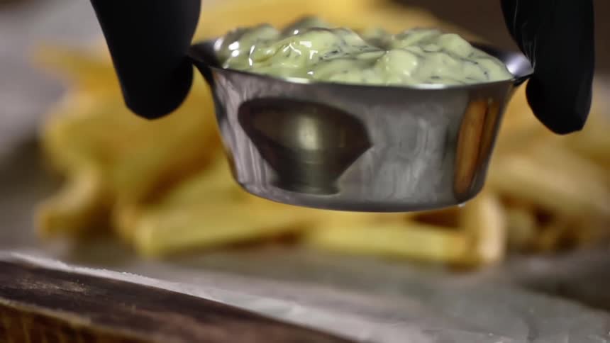 A person puts sauce on a platter with food